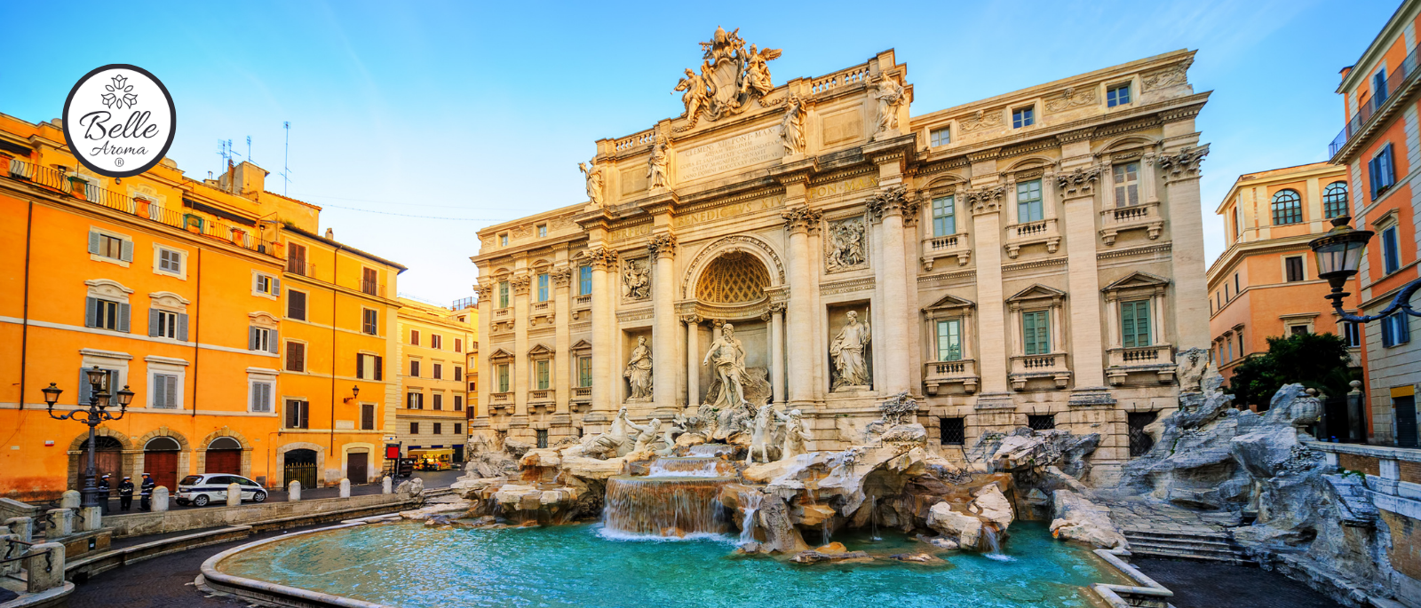 Trevi Fountain in Rome, Italy at sunrise, featuring the historic Baroque fountain, turquoise water, and surrounding European architecture with Belle Aroma® logo in the upper corner.