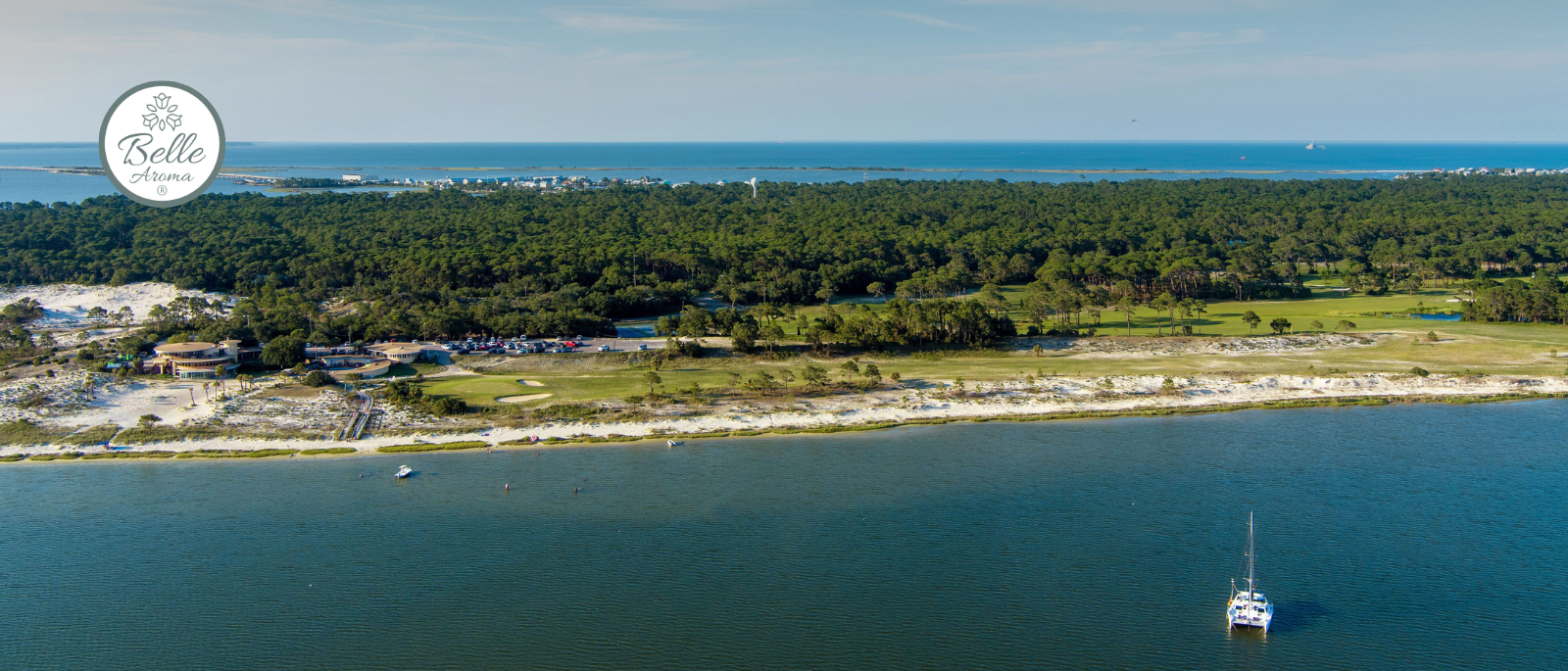 Aerial view of Dauphin Island, Alabama showing the coastline, forested island, and Gulf waters at sunset, featured in Belle Aroma’s Scents of Adventure travel blog.
