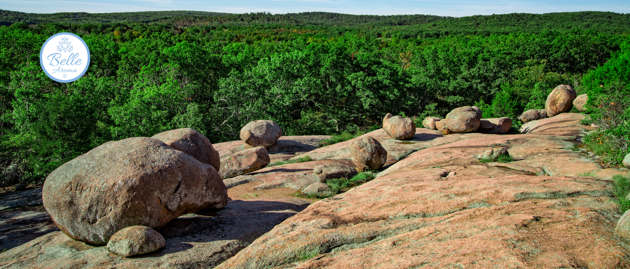 Elephant Rocks State Park in Missouri featuring massive pink granite boulders across a natural rock landscape, surrounded by lush green forest under blue sky, showcasing a scenic outdoor destination for hiking, nature walks, and day trips